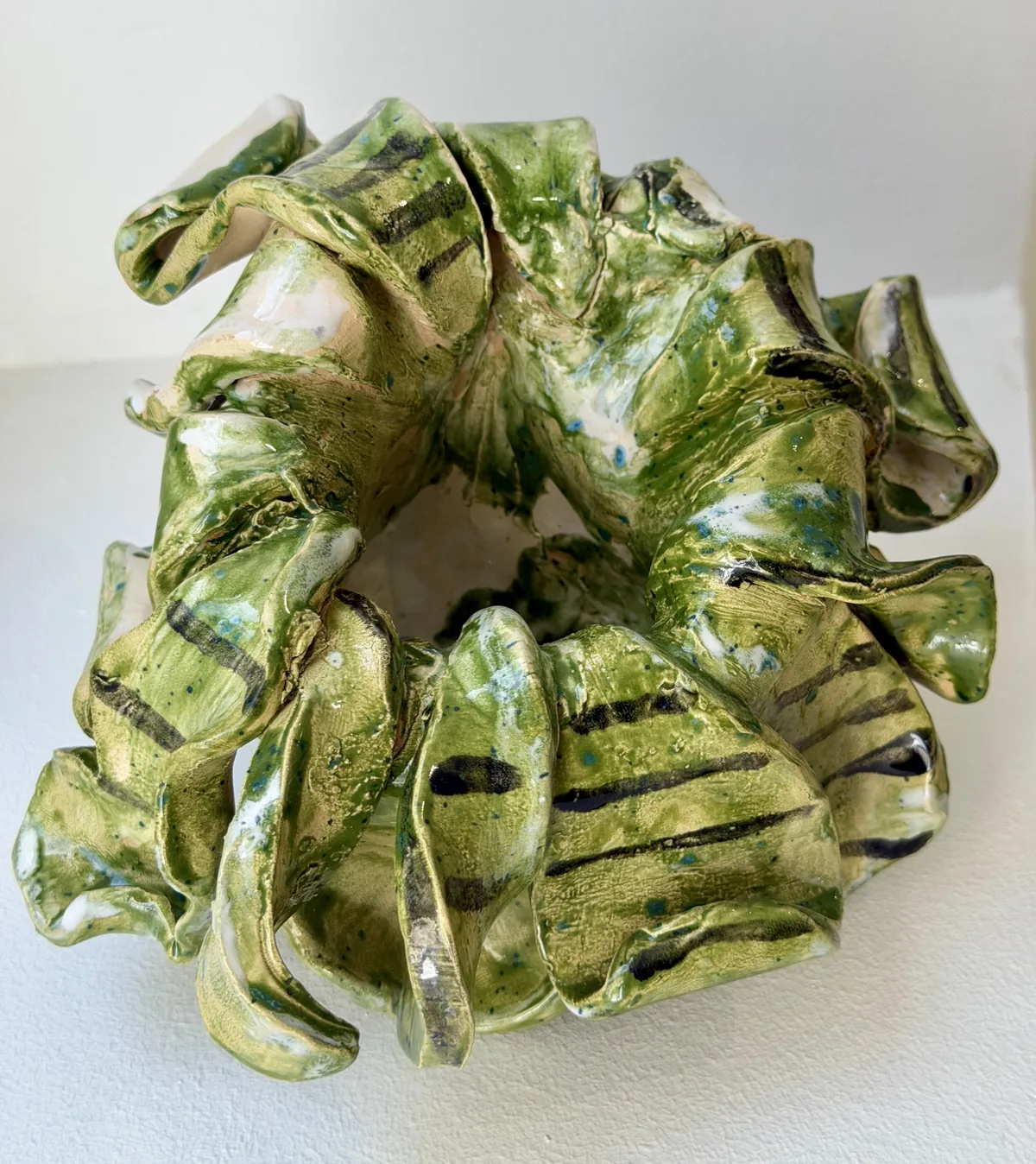Ceramic no. 13: a vase folded into drooping petals, apple-green glaze with black bands