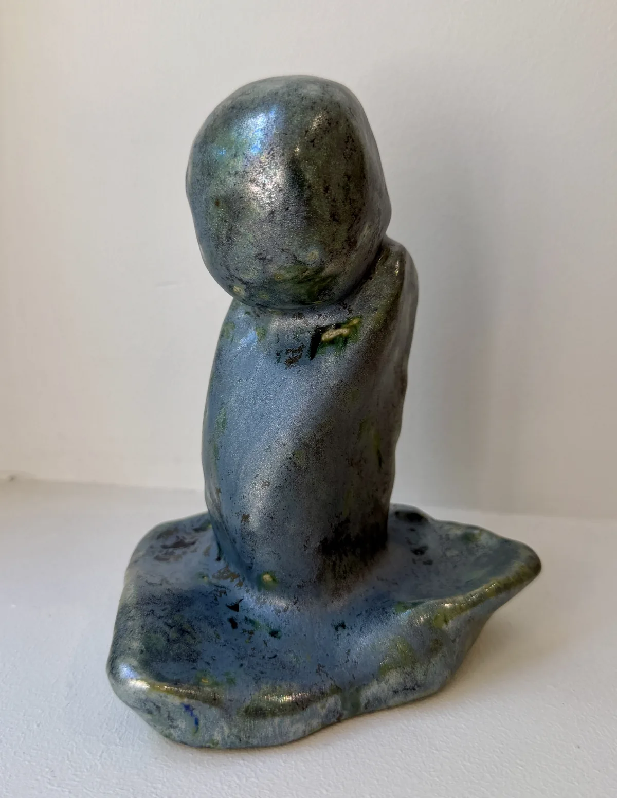 Ceramic no. 8: a faceless figure, a smooth round head on a draped body, grey-blue glaze