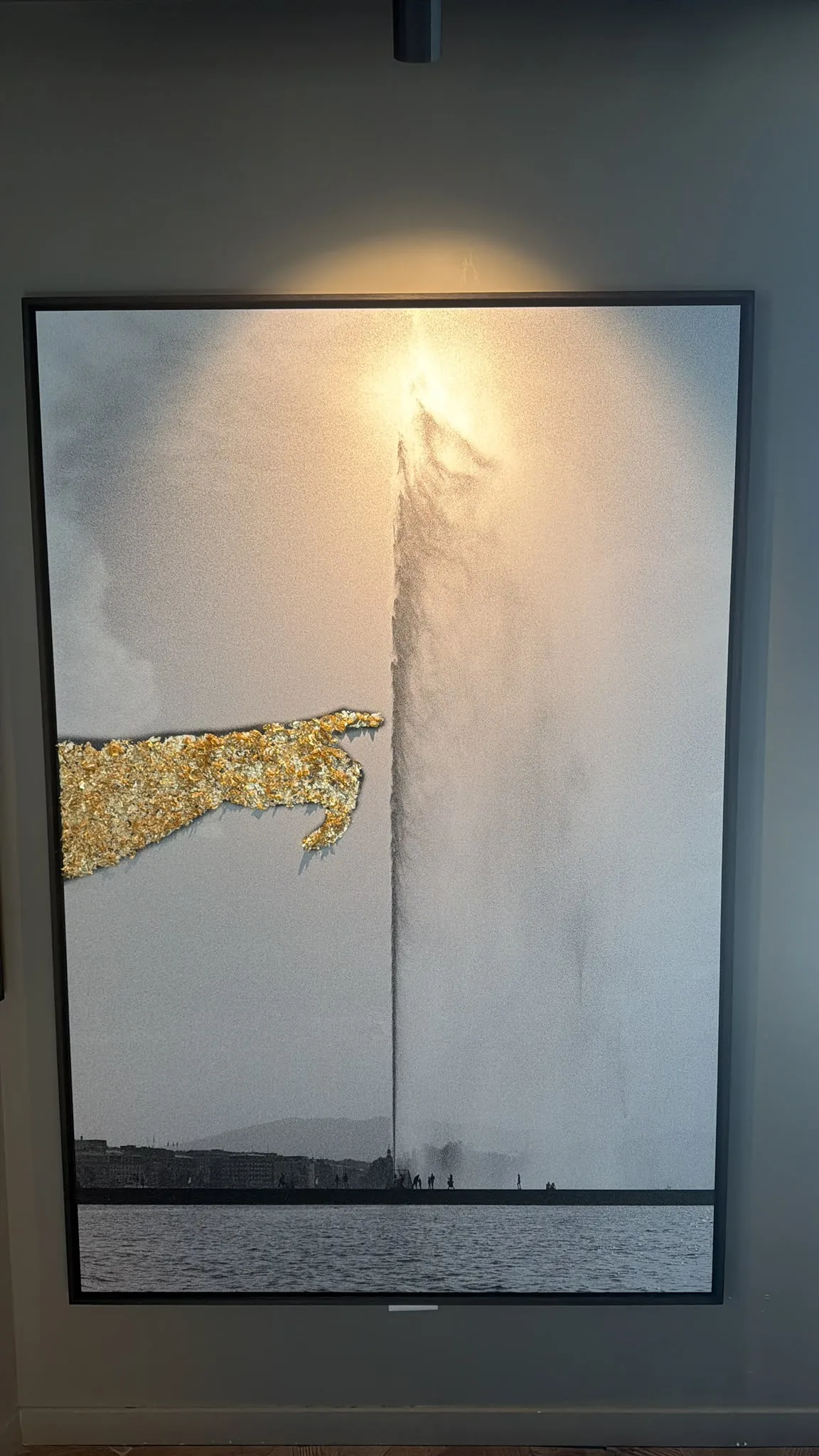 Jet d’Eau, Golden Hand hung on a dark wall under a spotlight, with its label