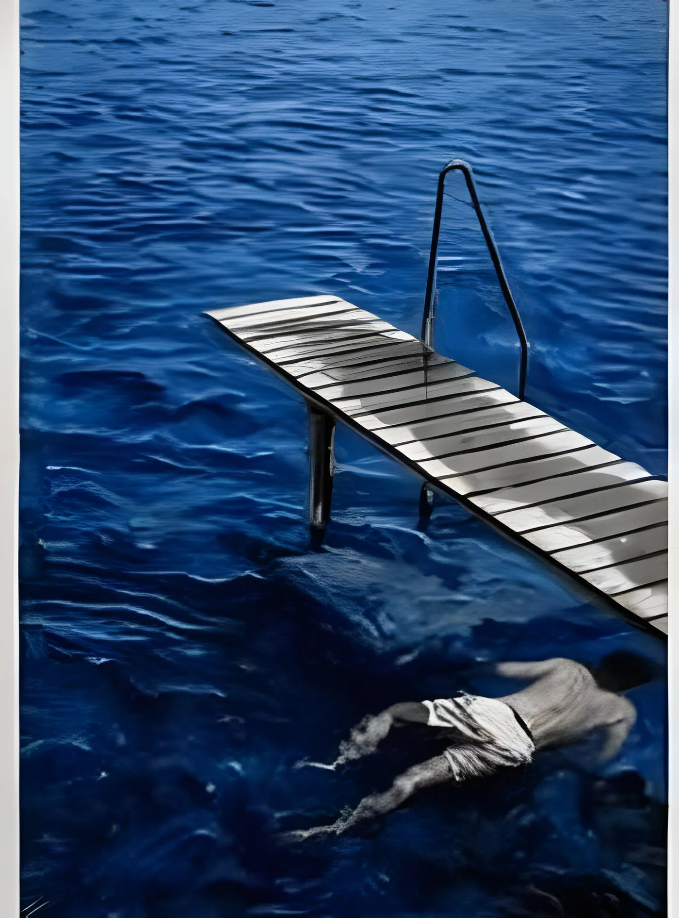The Jetty: a wooden jetty over painted blue water, a swimmer lying on the surface