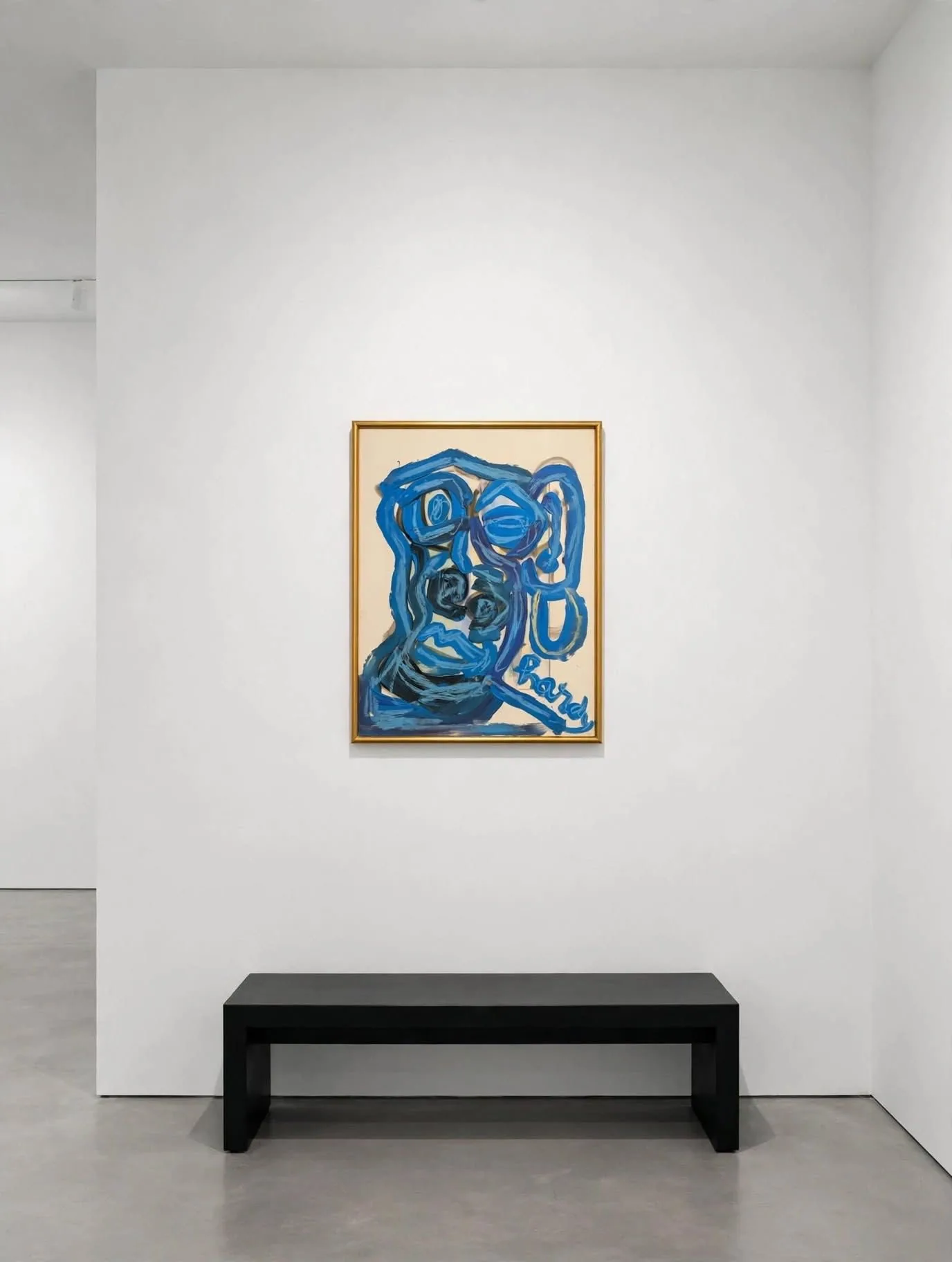 Blue Face in a gilt frame, in a white room with a black bench